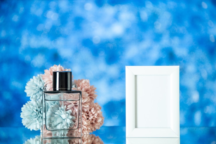Photo gratuit vue de face parfum féminin petit cadre photo blanc fleurs sur fond bleu flou espace libre