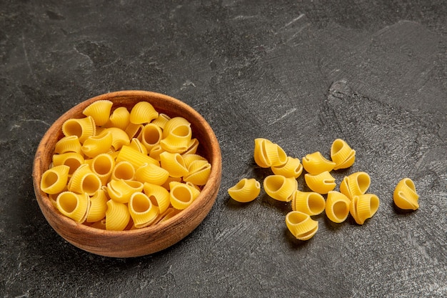 Vue de face des pâtes italiennes crues sur un espace gris