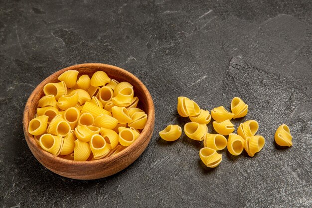 Vue de face des pâtes italiennes crues sur un espace gris