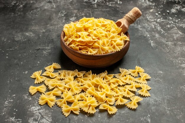 Vue de face des pâtes italiennes crues à l'intérieur de la plaque sur une photo de couleur gris foncé repas cuisine alimentaire