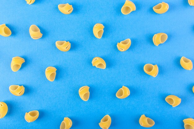 Une vue de face de pâtes jaunes isolées peu crues sur le fond bleu repas alimentaire pâtes spaghetti