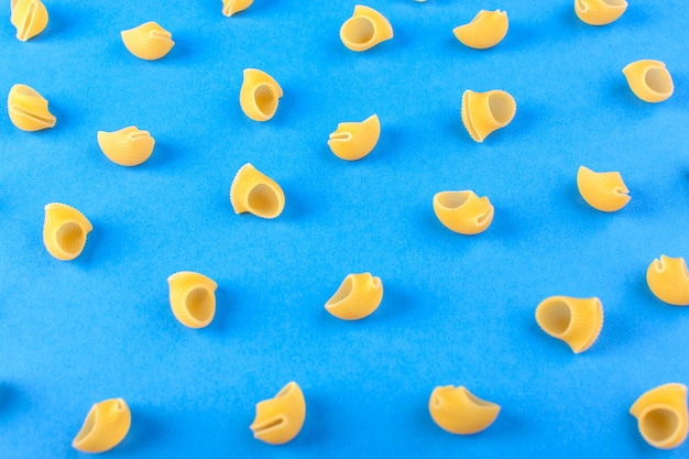 Une vue de face de pâtes jaunes isolées peu crues sur le fond bleu repas alimentaire pâtes spaghetti