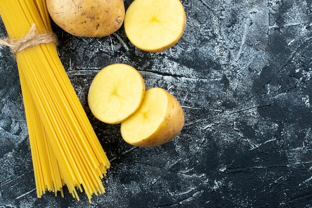 Vue de face des pâtes longues crues avec des pommes de terre sur un fond gris clair Pâte de pâtes de cuisine cuisine cuisine couleur cuisine