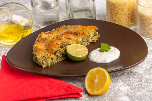 Vue de face de la pâtisserie avec de la viande délicieux repas de pâte à l'intérieur de la plaque avec de l'huile de citron sur un bureau blanc.