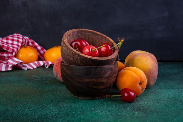 Vue de face pêches aux abricots et cerises dans des bols