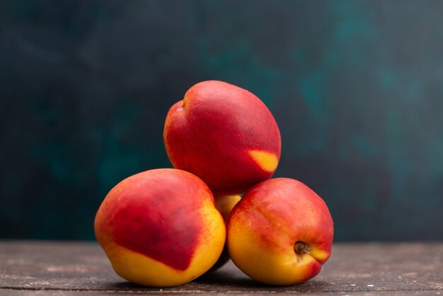 Vue de face pêches fraîches délicieux fruits sucrés sur la surface bleu foncé boisson aux fruits jus de fruits frais moelleux