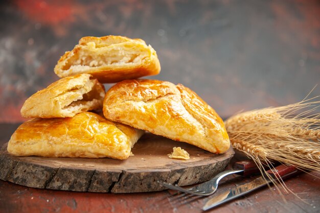 Vue de face penovani khachapuri sur un couteau et une fourchette en bois sur une table rouge foncé