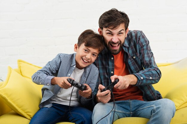 Vue de face père et fils jouant sur console