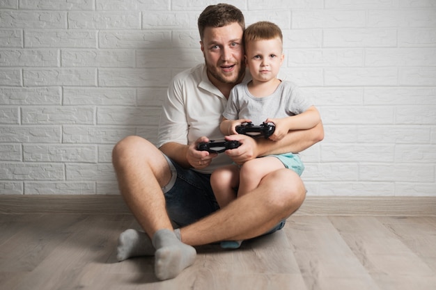 Vue de face père et fils jouant à des jeux vidéo