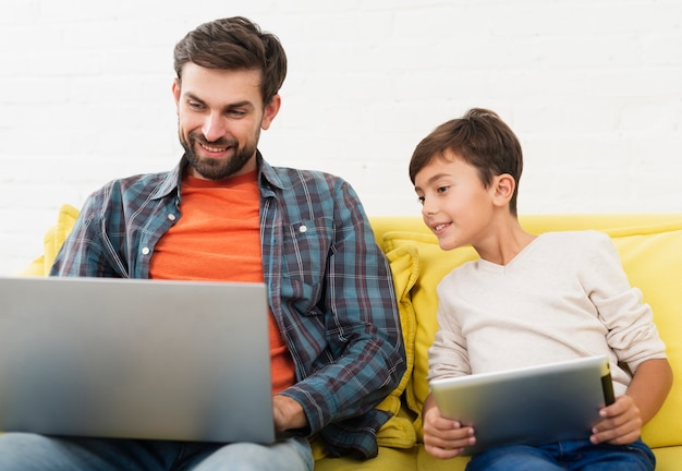 Vue de face père et fils à la recherche sur un ordinateur portable