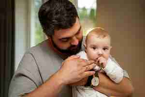 Photo gratuite vue de face père tenant bébé