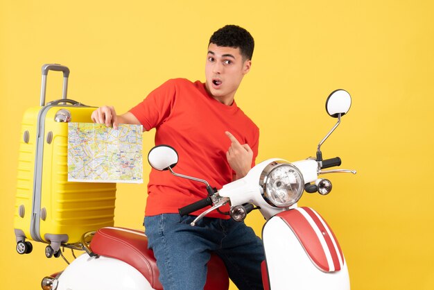 Vue de face perplexe bel homme sur la carte de tenue de cyclomoteur