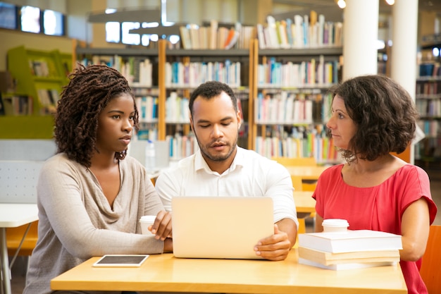 Vue de face de personnes réfléchies travaillant à la bibliothèque