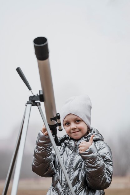 Vue de face petit enfant à l'aide d'un télescope