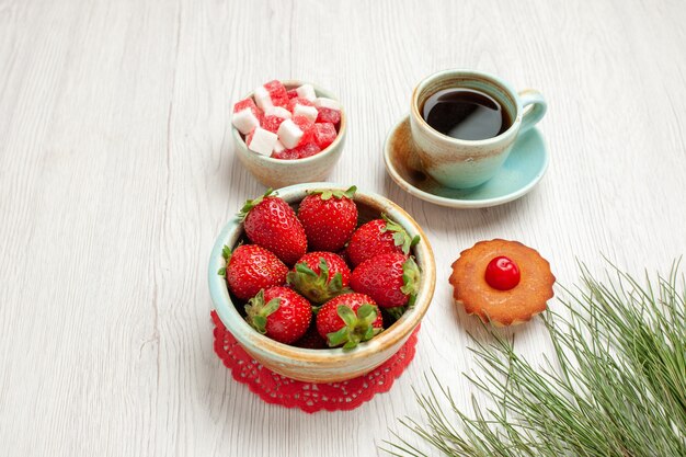 Vue de face petit gâteau aux fruits et tasse de thé sur un bureau blanc dessert thé gâteau aux fruits