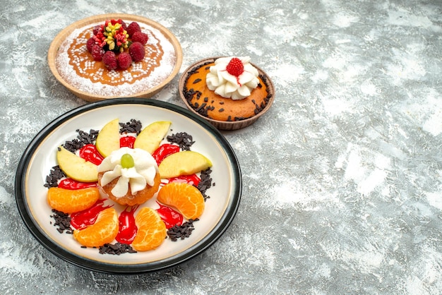 Vue de face petit gâteau aux fruits tranchés et tarte sur fond blanc gâteau aux fruits sucré biscuit biscuit au sucre