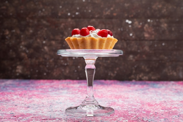 Photo gratuite vue de face petit gâteau délicieux avec de la crème et des fruits rouges sur la surface lumineuse sucrée