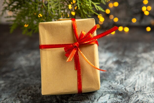 Vue de face petite branche de pin cadeau lumières de Noël sur fond sombre