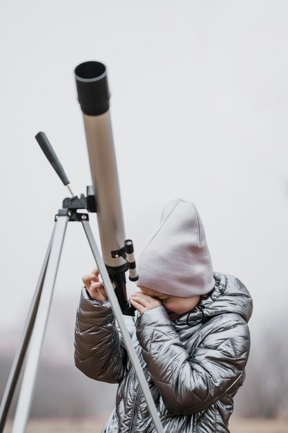 Vue de face petite fille à l'aide d'un télescope