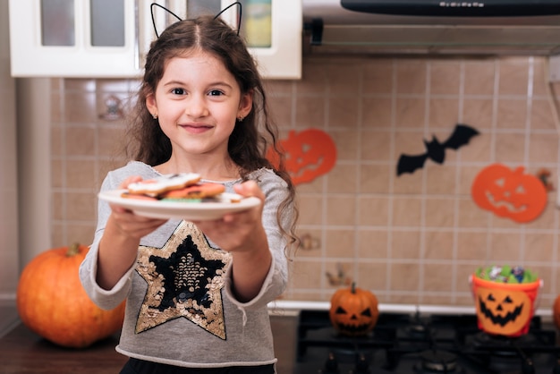 Vue de face d'une petite fille avec une assiette de biscuits