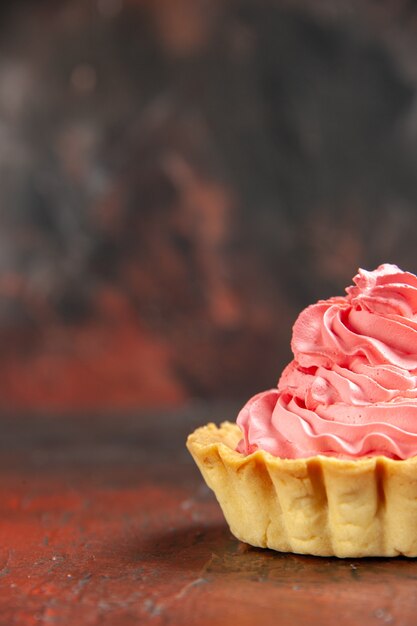 Vue de face petite tarte à la crème pâtissière rose sur l'espace de copie de table rouge foncé