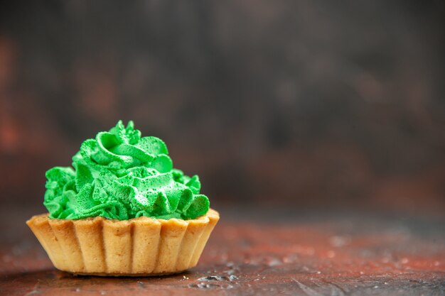 Vue de face petite tarte à la crème pâtissière verte sur table rouge foncé avec espace libre