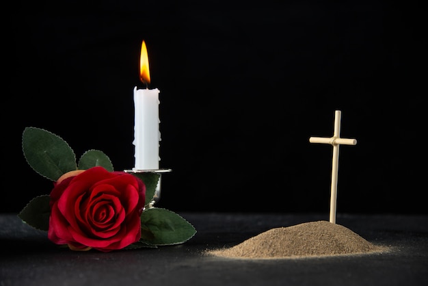 Vue de face de la petite tombe avec bougie et rose sur fond noir