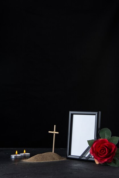Vue de face de la petite tombe avec croix et cadre photo sur fond noir