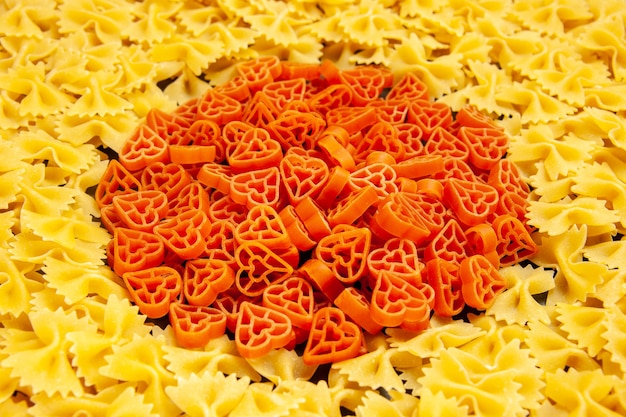 Photo gratuite vue de face de petites pâtes crues sur une photo de couleur foncée de nombreuses pâtes italiennes