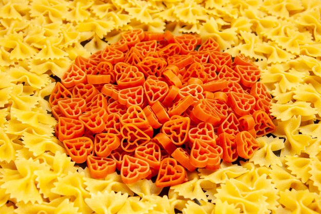 Vue de face de petites pâtes crues sur une photo de couleur foncée de nombreuses pâtes italiennes