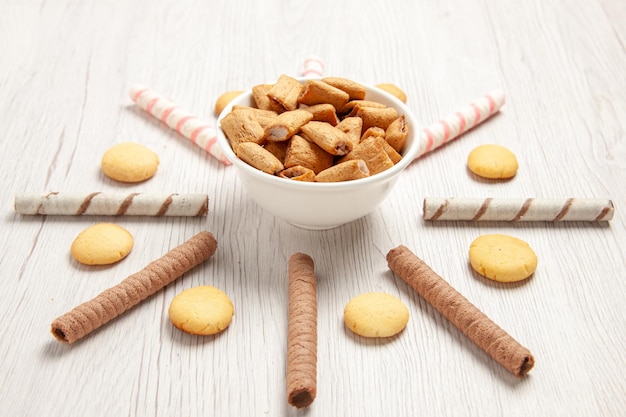 Vue de face de petits biscuits d'oreiller avec des biscuits sur du sucre de biscuit de biscuit de bureau blanc