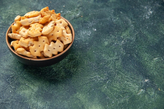 Vue de face petits craquelins salés à l'intérieur de la plaque sur fond sombre chips couleur snack cips sel poivre pain