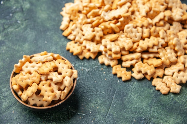 Photo gratuite vue de face petits craquelins salés à l'intérieur de la plaque et sur fond sombre couleur croquante cips sel poivre pain biscotte sèche nourriture