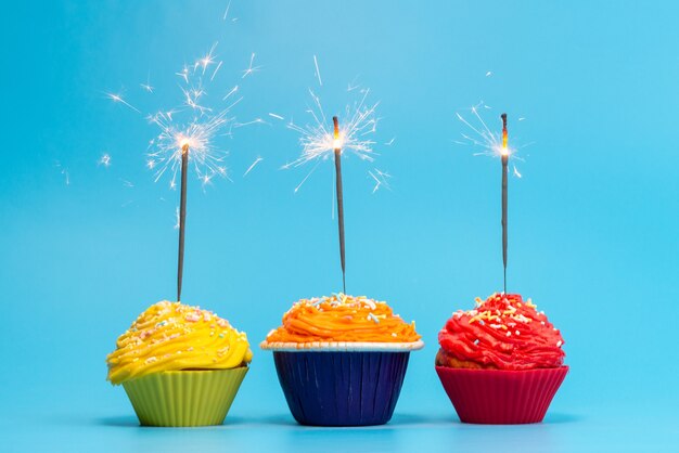 Une vue de face petits gâteaux colorés délicieux isolés sur bleu, couleur célébration biscuit