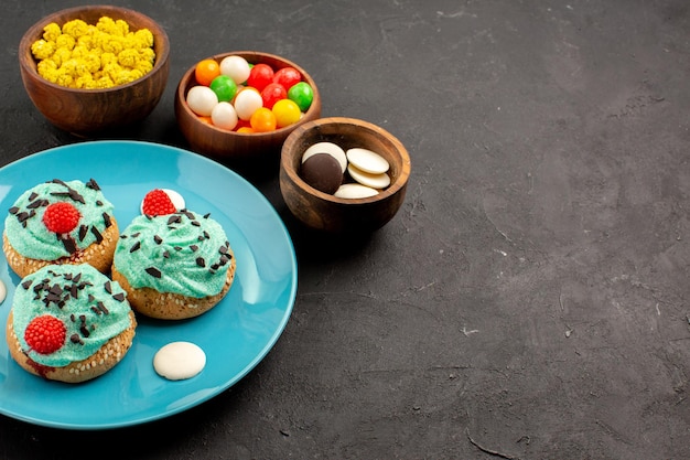 Vue de face petits gâteaux crémeux avec des bonbons sur fond gris foncé dessert gâteau couleur biscuit crème de bonbons