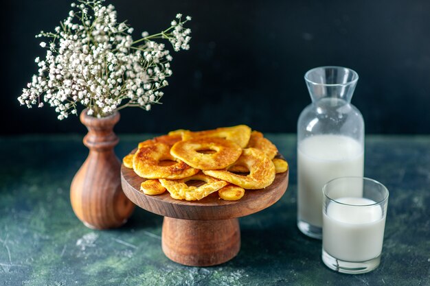 Vue de face de petits gâteaux délicieux en forme d'anneau d'ananas sur une tarte aux fruits noirs