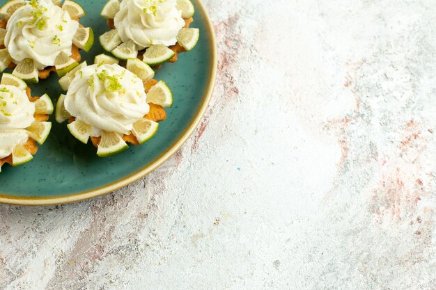 Vue de face de petits gâteaux délicieux avec des tranches de citron sur une surface blanche claire