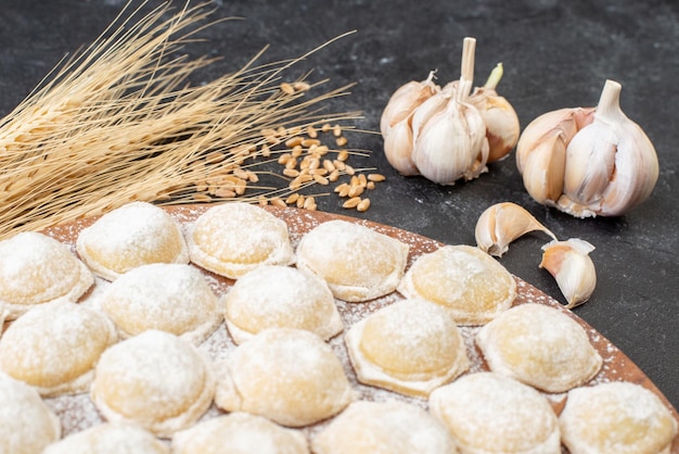 Vue de face petits morceaux de pâte avec de la farine sur un fond sombre boulette de pâte pain viande hotcake tarte gâteau de couleur