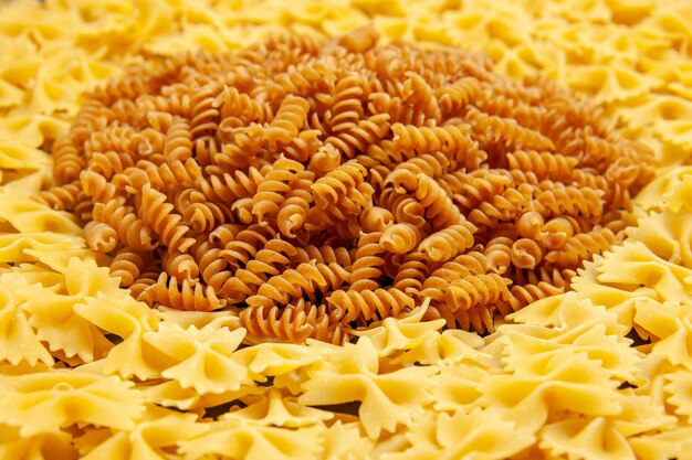 Vue de face peu de pâtes crues sur photo de couleur foncée beaucoup de pâte repas de pâtes italiennes