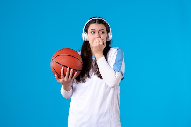 Vue de face peur jeune femme avec des écouteurs tenant le basket-ball