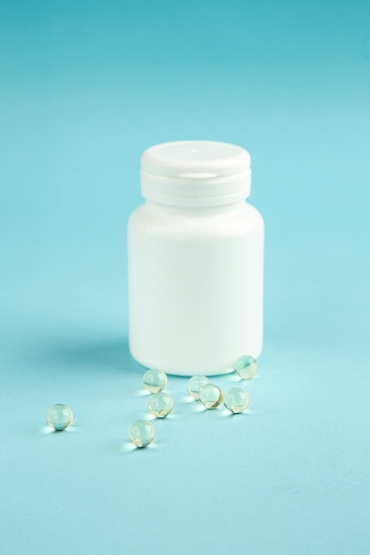 Vue de face en plastique blanc peut avec des pilules sur fond bleu