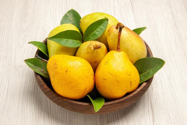 Vue de face poires douces fraîches fruits sucrés à l'intérieur de la plaque sur des fruits de bureau blanc jaune frais sucré mûr