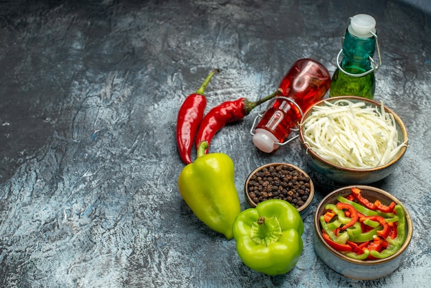 Photo gratuite vue de face de poivrons frais avec du chou tranché et du liquide sur une table gris clair