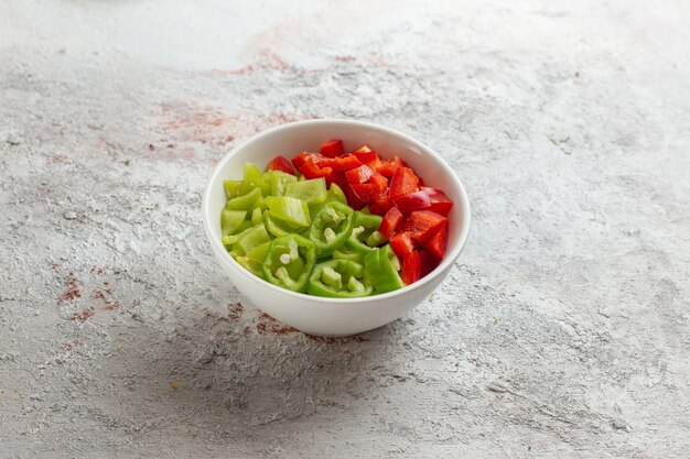 Vue de face poivrons tranchés à l'intérieur de la petite assiette sur la surface claire