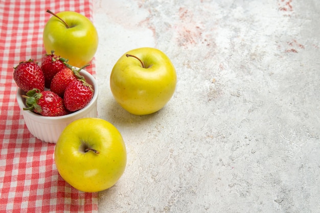 Vue de face des pommes fraîches avec des baies rouges sur une table blanche couleur baies de fruits