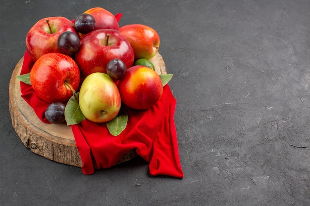 Vue de face des pommes fraîches avec des pêches et des prunes sur la table sombre arbre à jus mûr et moelleux