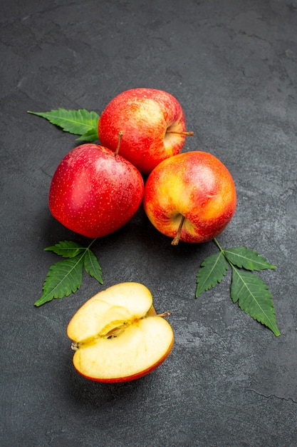 Vue de face des pommes rouges fraîches entières et coupées et des feuilles sur fond noir