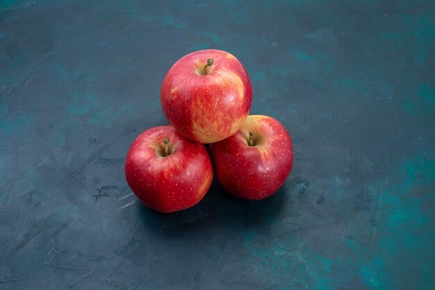 Vue de face des pommes rouges fraîches fruits moelleux et frais sur le bureau bleu foncé fruits frais mûrs mûrs