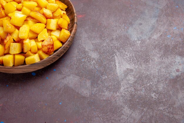 Vue de face de pommes de terre cuites tranchées à l'intérieur de la plaque sur un espace sombre