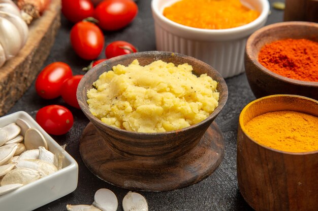 Vue de face purée de pommes de terre avec assaisonnements et tomates sur fond gris couleur repas tarte produit mûr